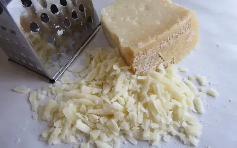 Tarka metalowa i kawałek sera z garścią startego sera.