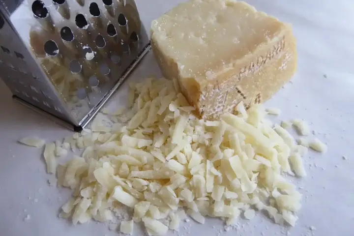 Tarka metalowa i kawałek sera z garścią startego sera.