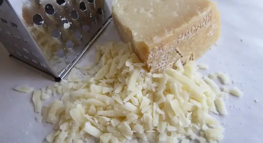 Tarka metalowa i kawałek sera z garścią startego sera.